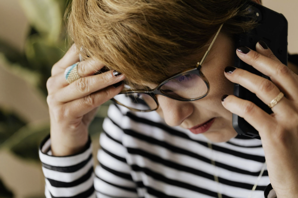Person in glasses holding head in hands, appearing stressed